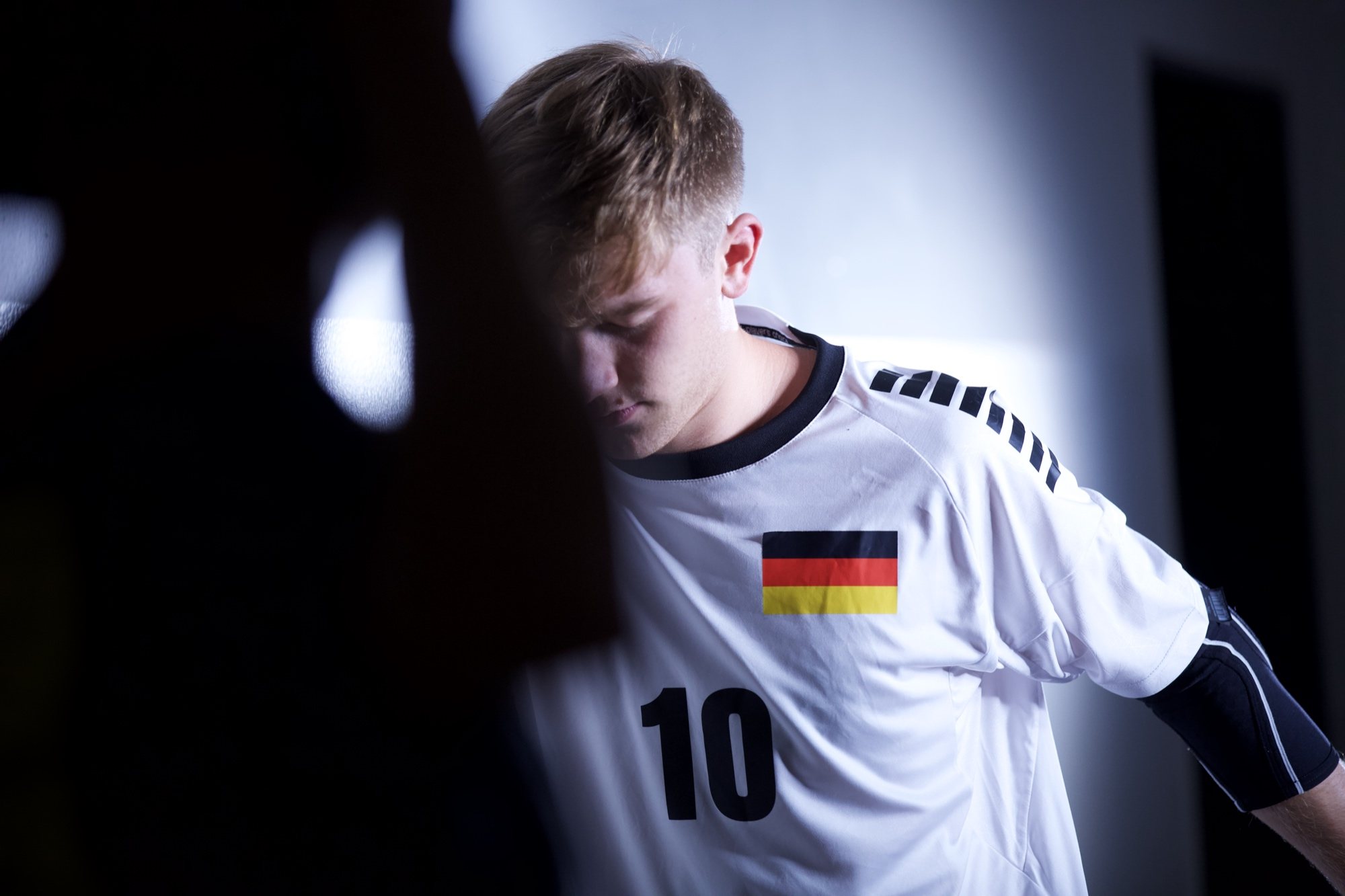 Hauptdarsteller im Trikot mit der Nummer 10 im dunklen Korridor, Kopf gesenkt